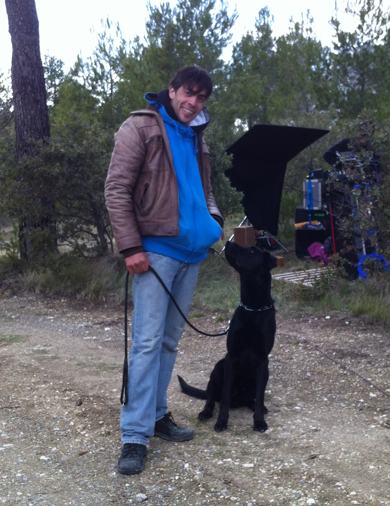 Brice Thomas et un chien noir sur un tournage, en extérieur